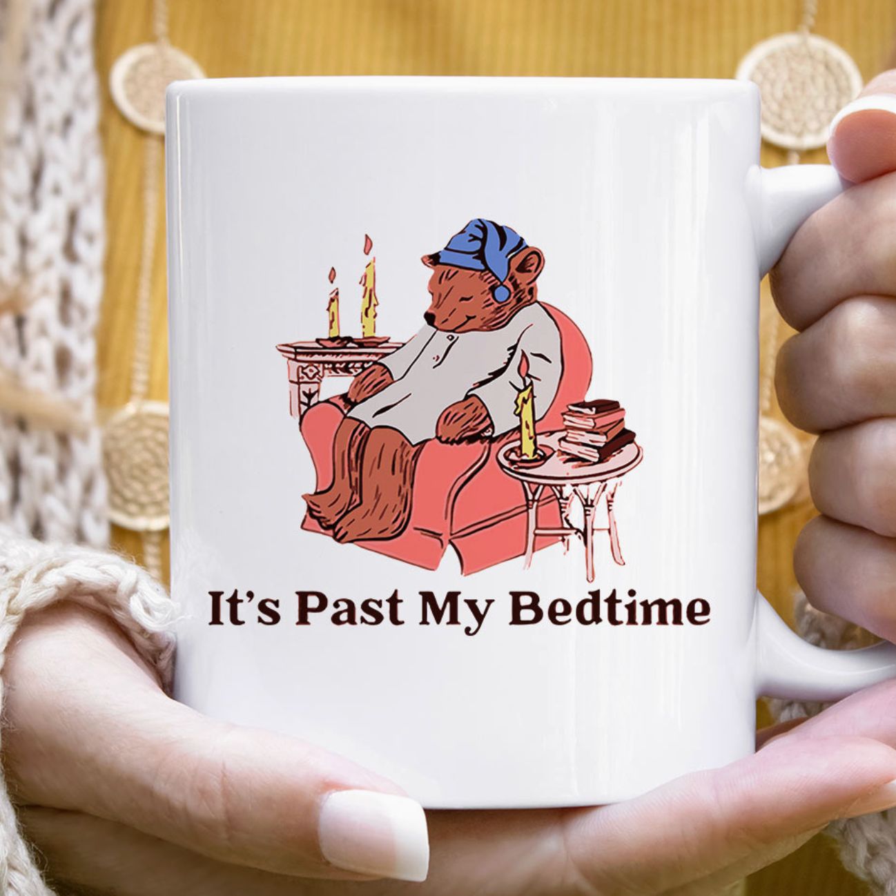 Mug with cartoon bear holding candles and text 'It's Past My Bedtime' held by a person.