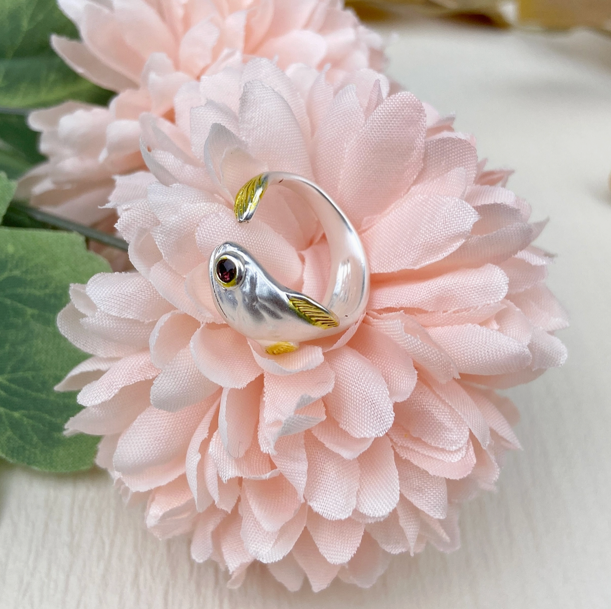 Silver ring with a fish design on a pink flower