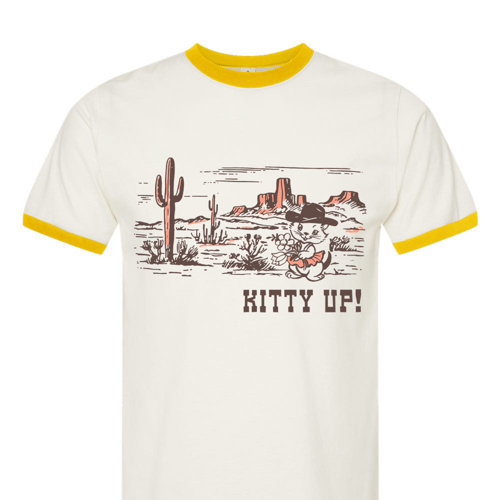 White t-shirt with yellow trim featuring a desert scene and 'Kitty Up!' text on a white background