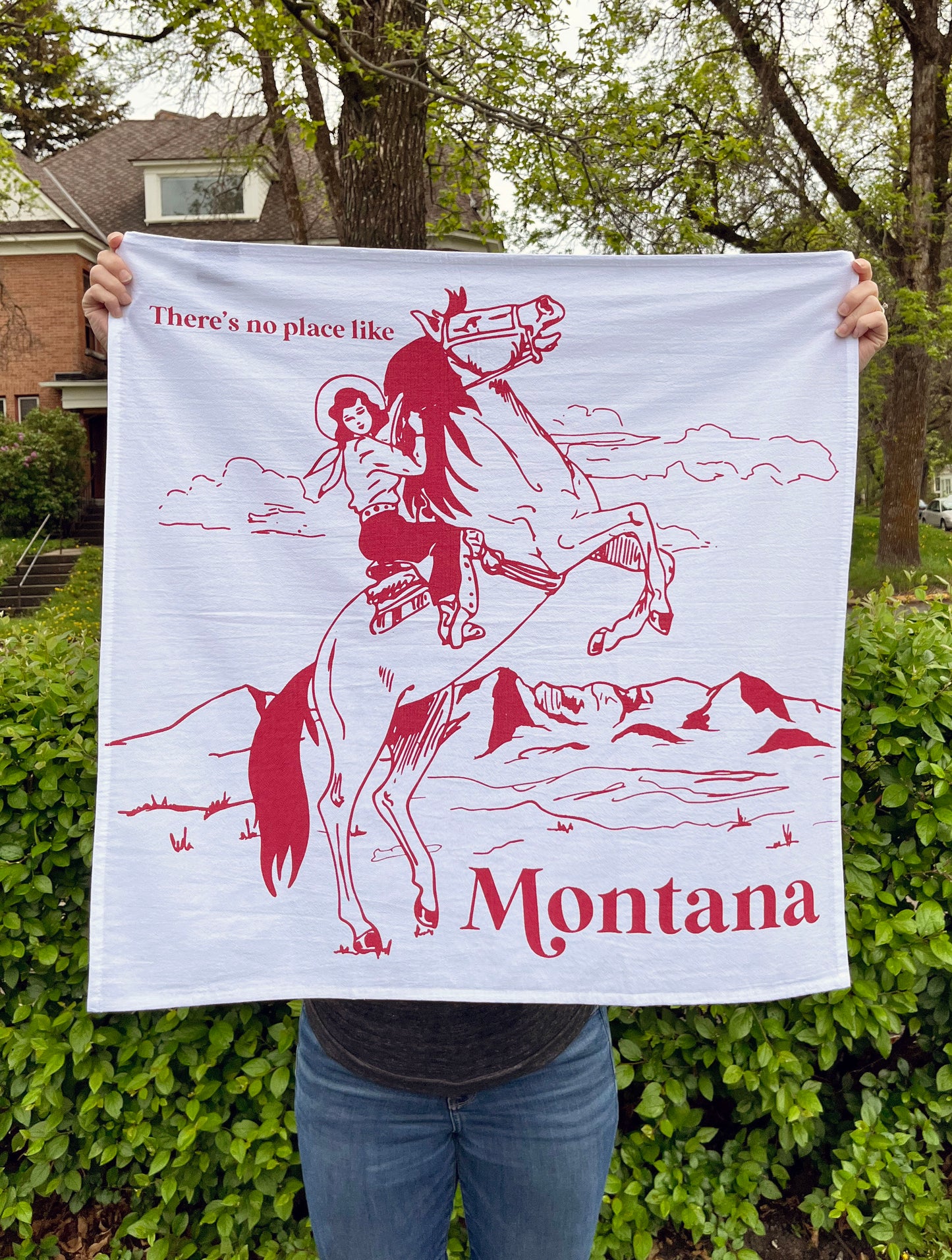 all over screen print on cotton dish towel theres no place like montana cowgirl riding bucking bronco horse red print fun gifts and souvenirs coin laundry montana