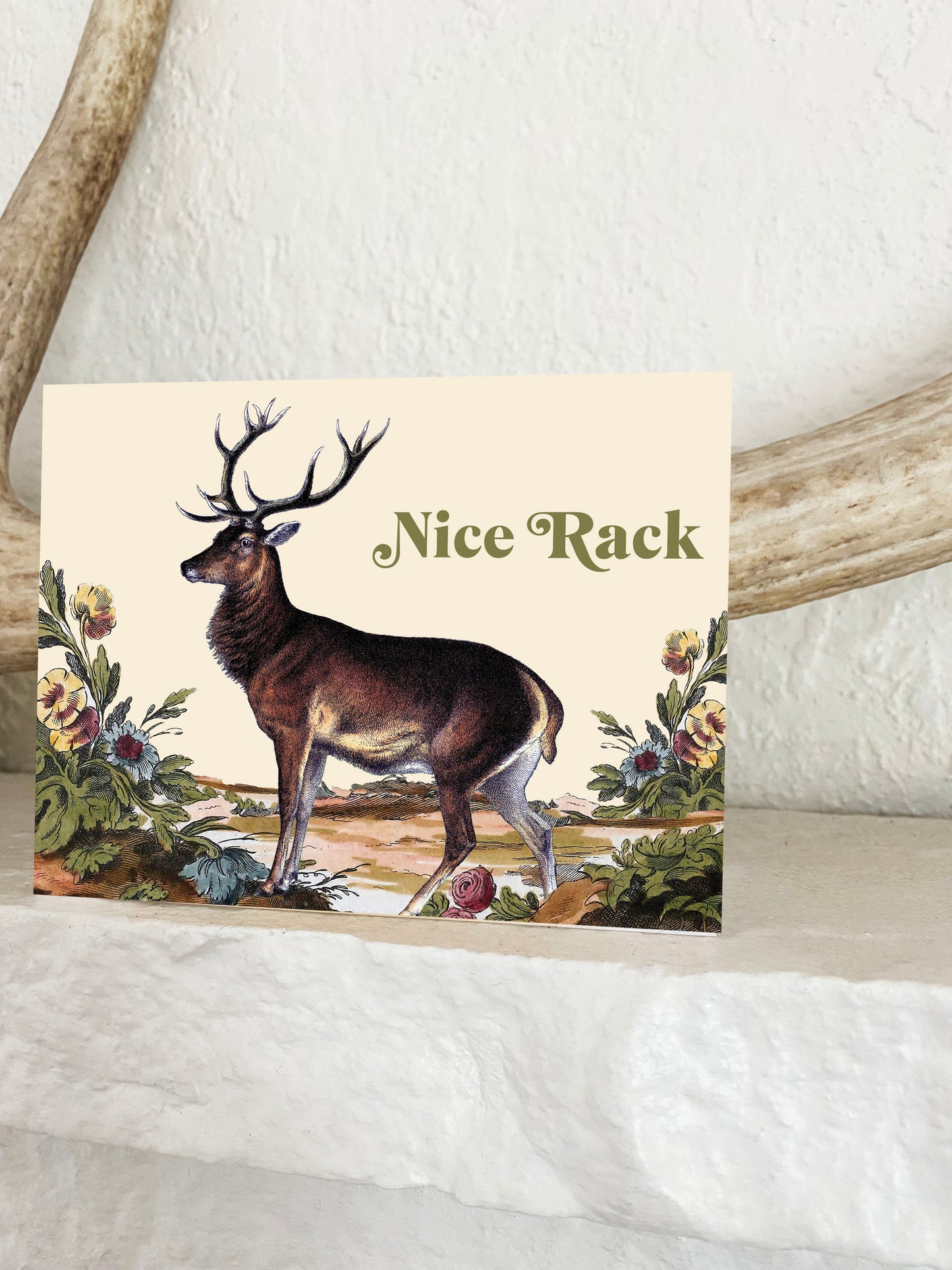 Vintage illustration of deer with large antlers next to wildflowers with text Nice Rack