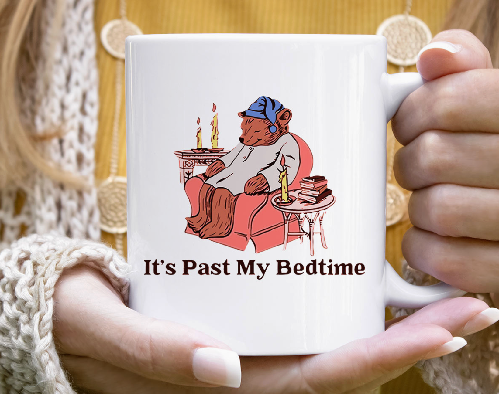 Mug with cartoon bear holding candles and text 'It's Past My Bedtime' held by a person.
