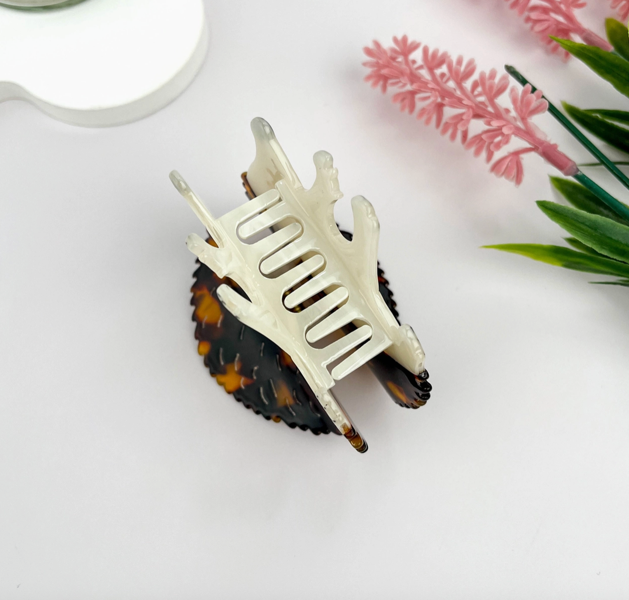 White hair clip on a tortoise shell with pink flowers in the background
