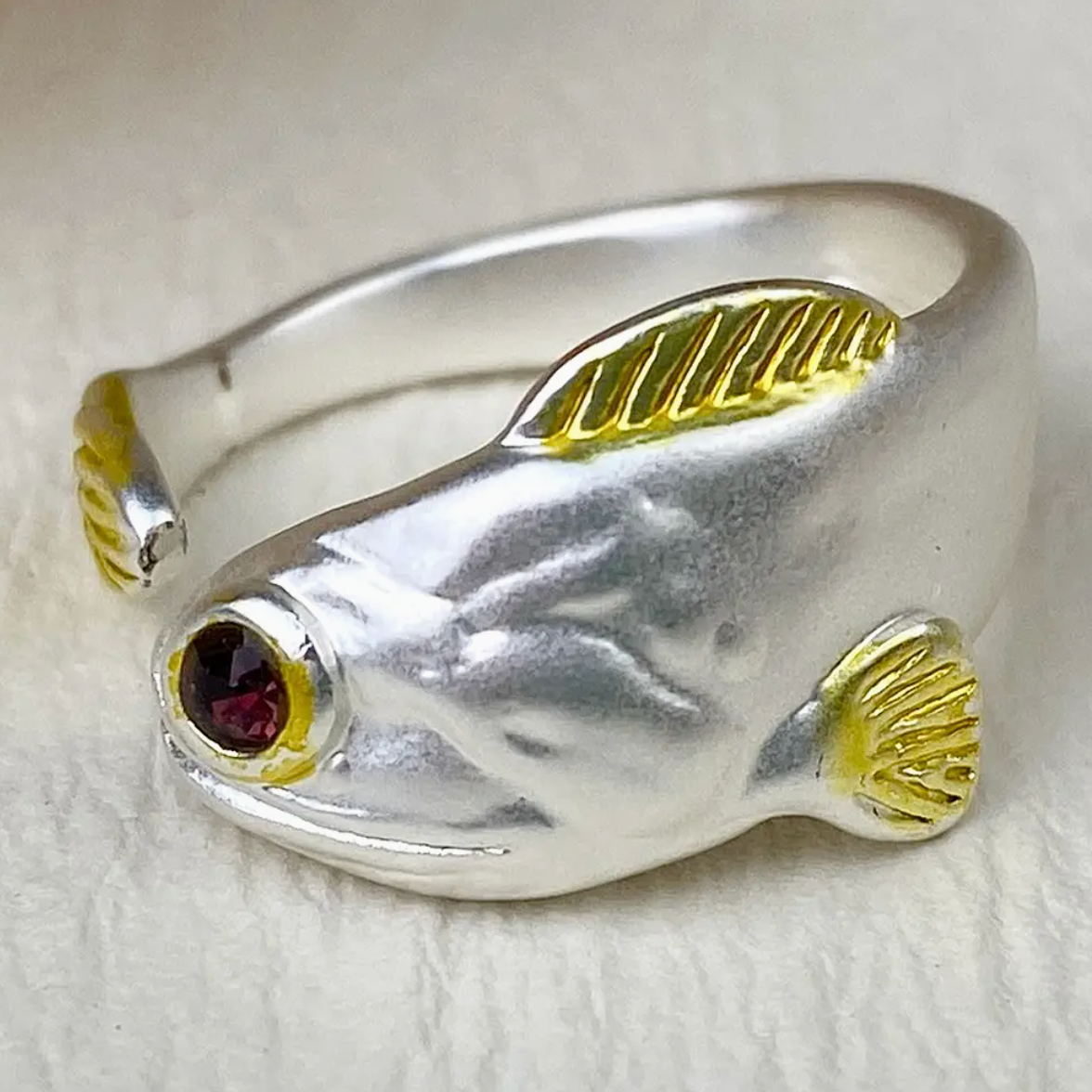 Silver fish-shaped ring with gold accents on a white background