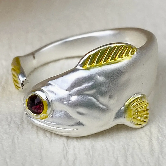 Silver fish-shaped ring with gold accents on a white background