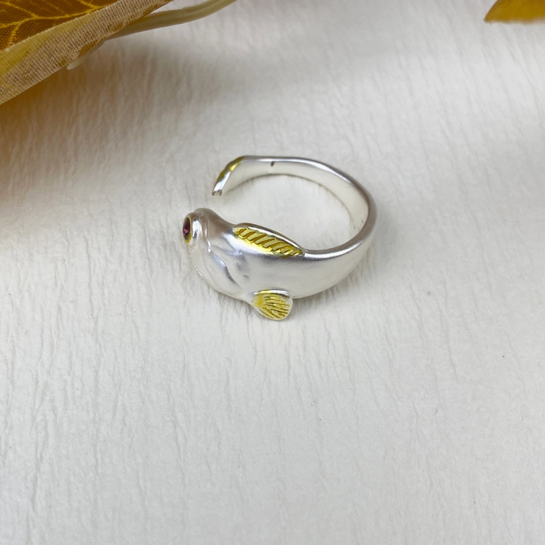 Silver ring with gold accents on a light wooden surface