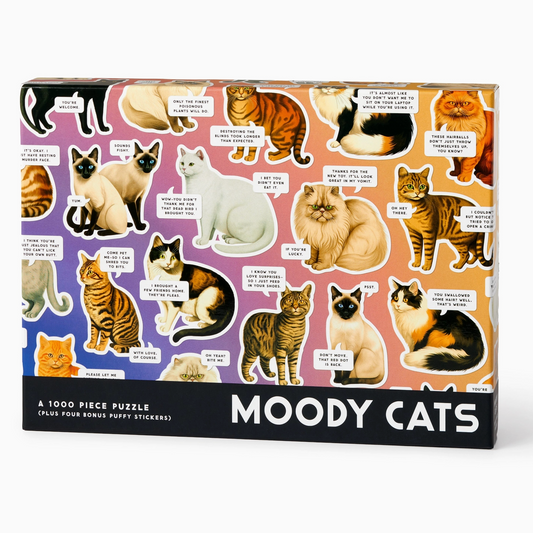 A 1000-piece jigsaw puzzle box titled 'MOODY CATS' featuring a colorful collage of various cat illustrations with humorous text labels on a pink, purple, and orange background.