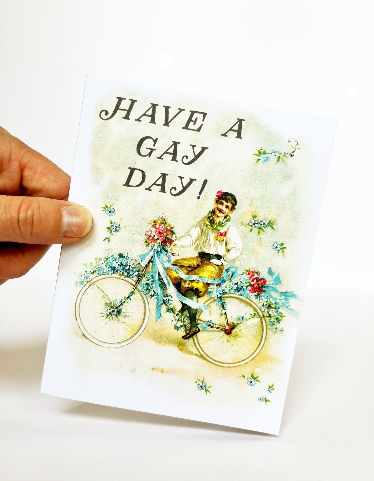 old timey vintage boy man with mustache on bicycle flowers ribbons have a gay day flamboyant celebratory just because all purpose birthday lgbtq queer gay lesbian nonbinary pride pastel pretty cute fun joyful coin laundry  