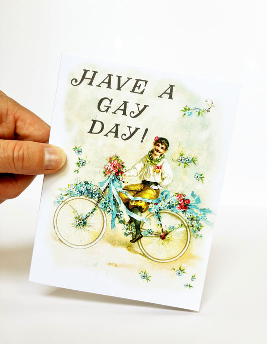 old timey vintage boy man with mustache on bicycle flowers ribbons have a gay day flamboyant celebratory just because all purpose birthday lgbtq queer gay lesbian nonbinary pride pastel pretty cute fun joyful coin laundry