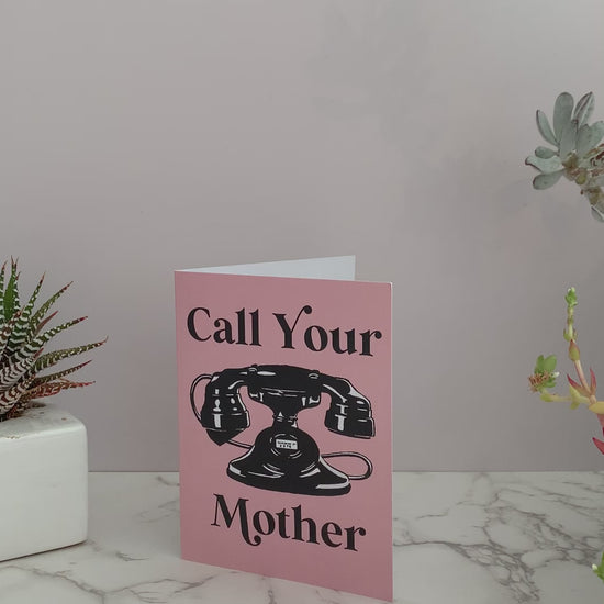 Pink greeting card with black vintage rotary telephone. Front says "Call Your Mother." Blank inside. retro style fun funny mother's day send to college student kid at camp adult child