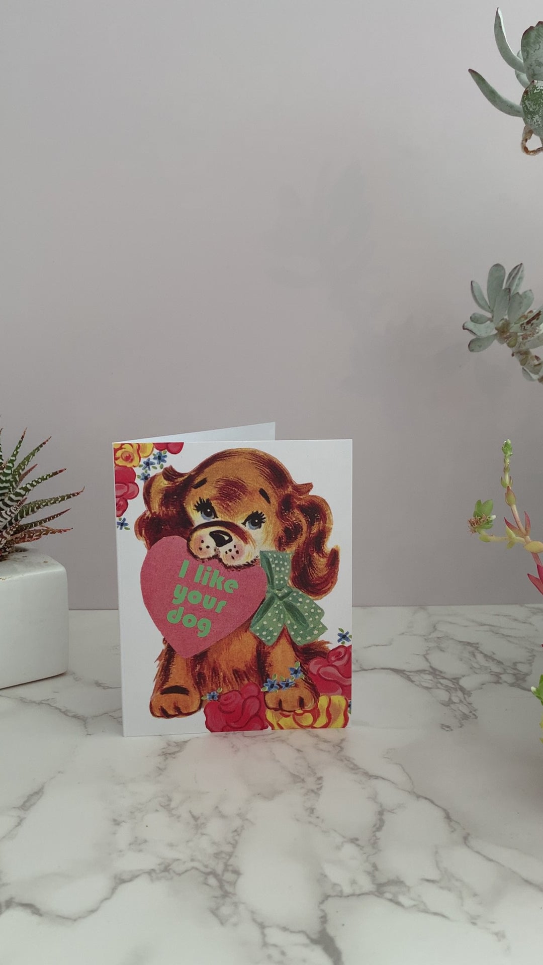 The perfect card to give to your crush, your best friend, or for Valentine's Day. Featuring a brown vintage puppy dog holding a heart in it's mouth, surrounded by pink and yellow flowers. Greeting says, "I like your dog." Blank inside. 
