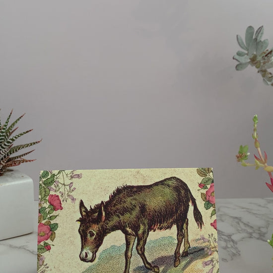 Greeting card perfect to send to your crush, your husband, your wife, your best friend, Valentine's day, or any occasion. Featuring an image of a brown vintage donkey surrounded by flowers. Color pallet is yellows, pinks, greens and blues. Greeting says, "You have a great ass." on the front. Blank inside.