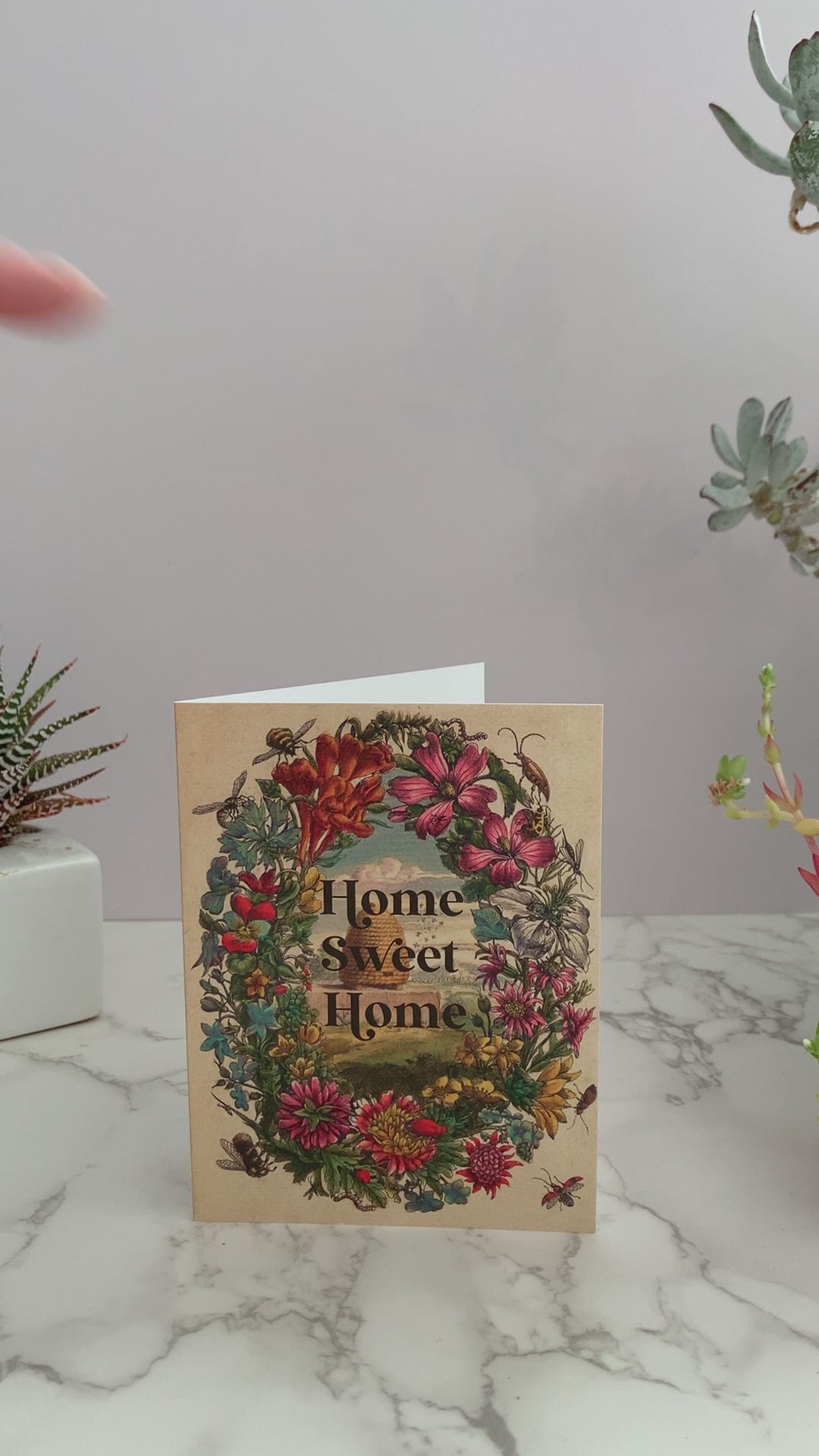 Perfect greeting card for a house warming, a move, or congratulations on purchasing a new home. Vintage image featuring a beehive surrounded by a floral frame and bees. Greeting says, "Home Sweet Home." Color pallet is vintage colors of pinks, reds, blues, greens, and yellows. Blank inside.