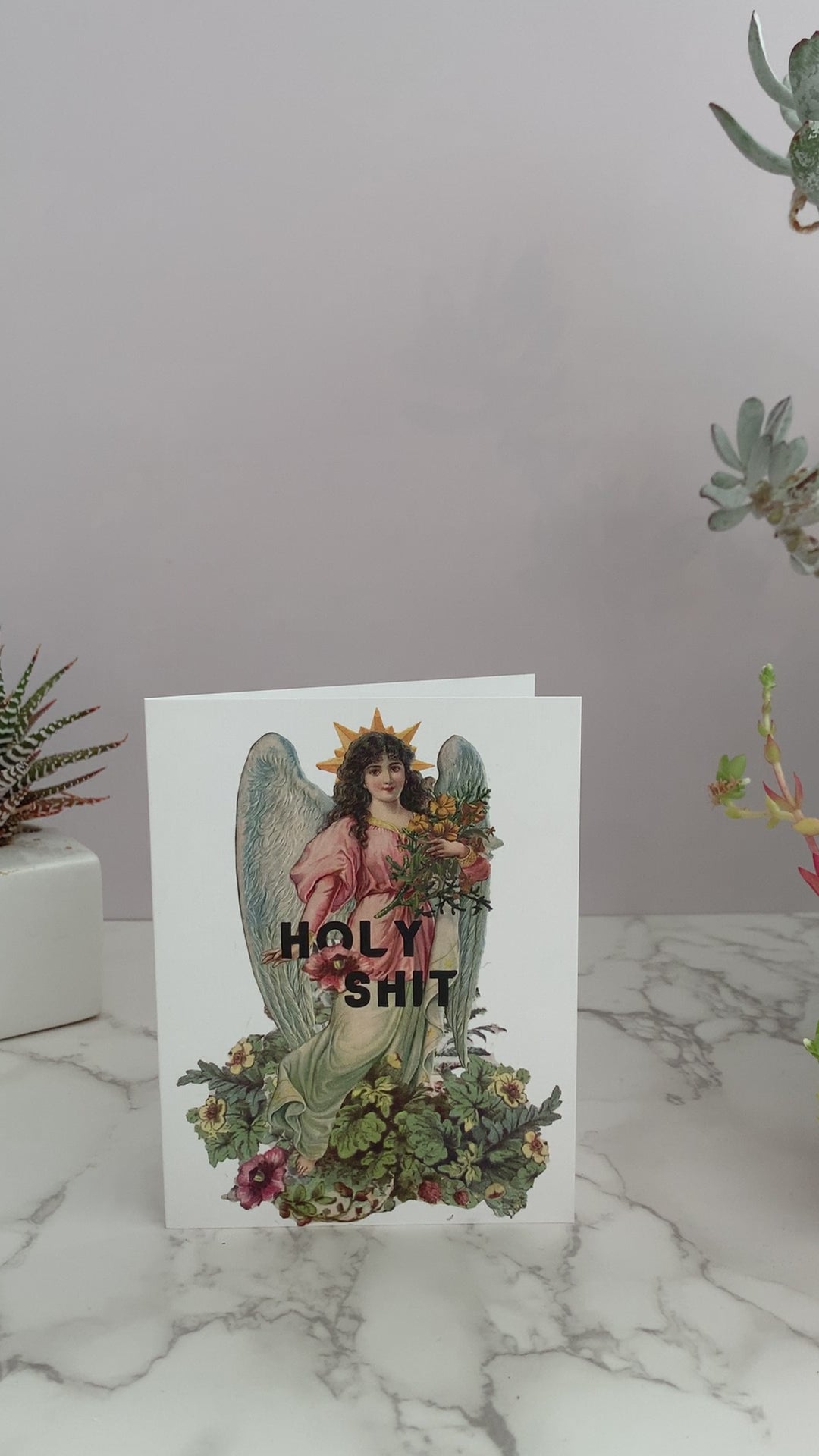 All purpose greeting card perfect for any occasion, like birthdays, celebrations, or just because. White card that features a vintage angel with flowers. Greeting says, "Holy Shit." Vintage colors of pinks, blues, greens, and yellows. Blank inside