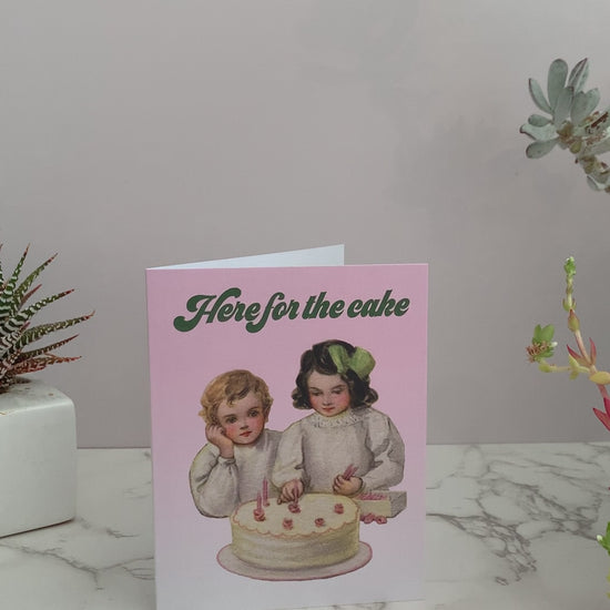 All purpose greeting card. Can be used for celebrations, birthdays, weddings, anniversaries, or anything. Front of the card is light pink, with a vintage image of two children putting candles on a cake. Greeting says, "Here for the cake." Inside is blank.