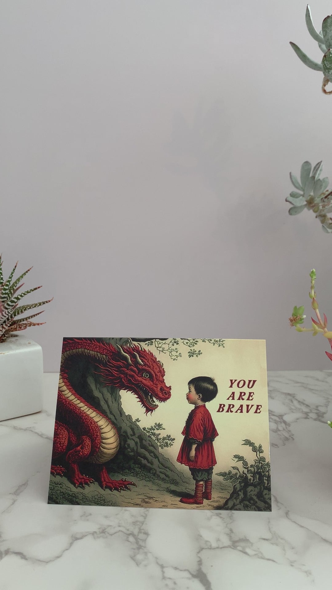 All purpose greeting card that says "You are Brave" on the front. Vintage images featuring a little boy calmly  staring into the face of a large red dragon, next to a tree. Color pallet is reds, yellows, and greens. Blank inside. Perfect to send to a friend who is going through a big life change.