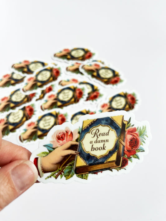 read a damn book sticker vintage style hand holding book with flowers stickers for smart people stickers for readers snarky sarcastic stickers coin laundry montana 